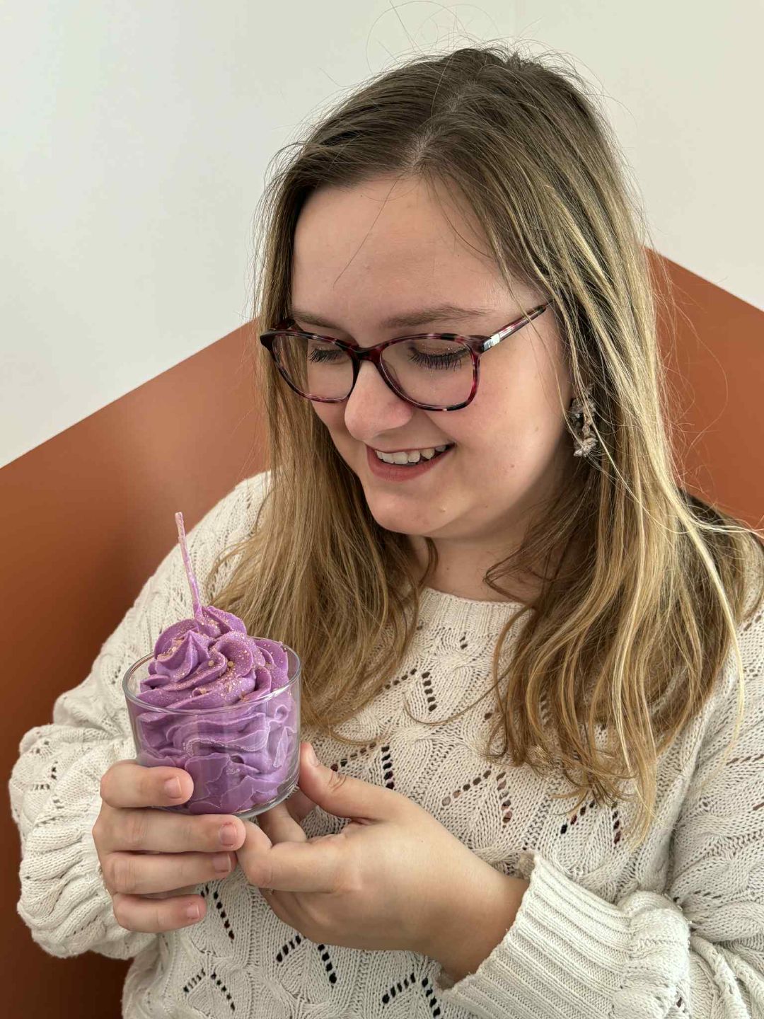 Femme créant une bougie artisanale dans un atelier chaleureux avec des bougies colorées en arrière-plan