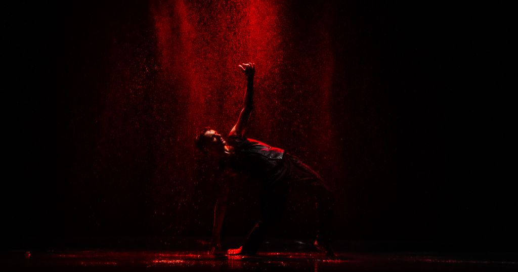 Tournage de clip musical sous la pluie, artiste en mouvement avec effets de lumière