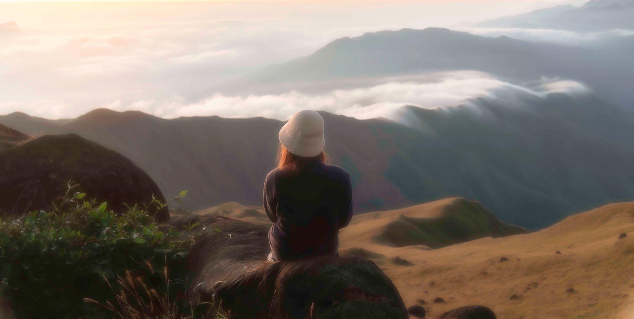 Femme voyageant seule avec sac à dos, regardant un paysage magnifique avec confiance et liberté